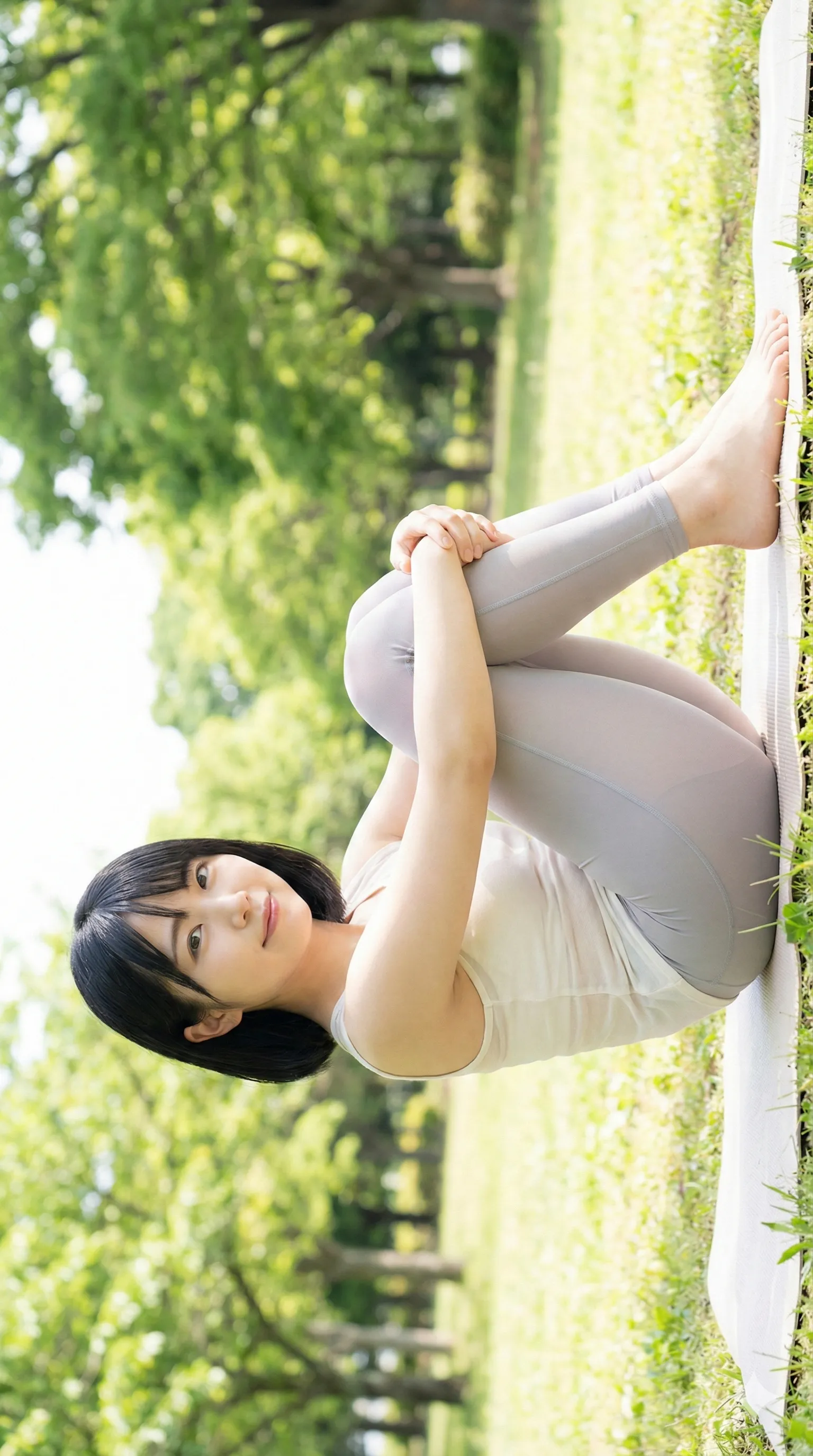 レギンス姿の女性が芝生で脚を抱えるポーズ02